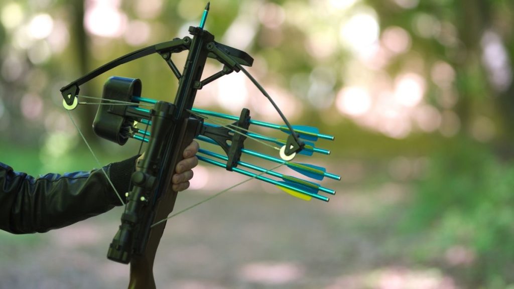 A crossbow hunter is holding his crossbow.