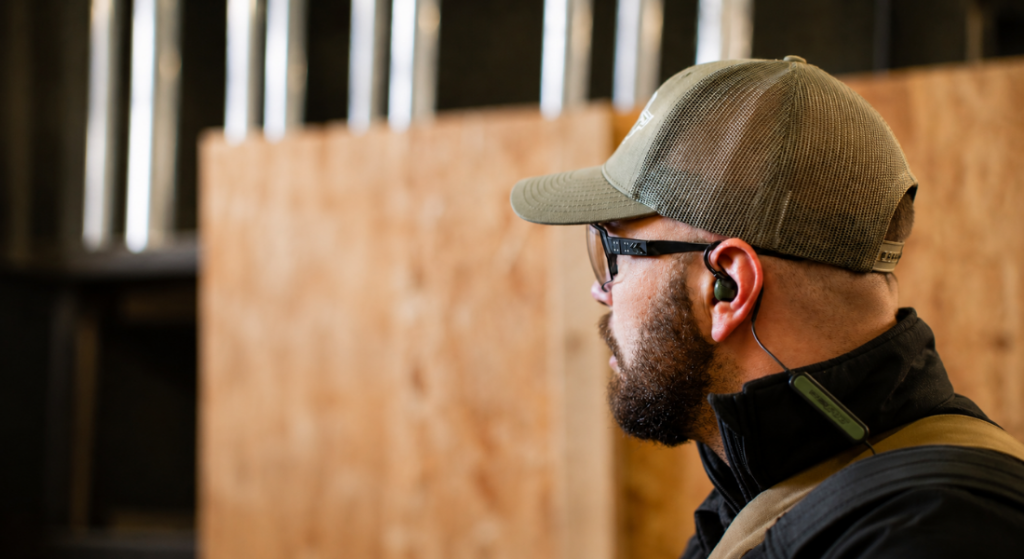 Man wearing wired electronic earplugs and safety glasses during a shooting range session.
