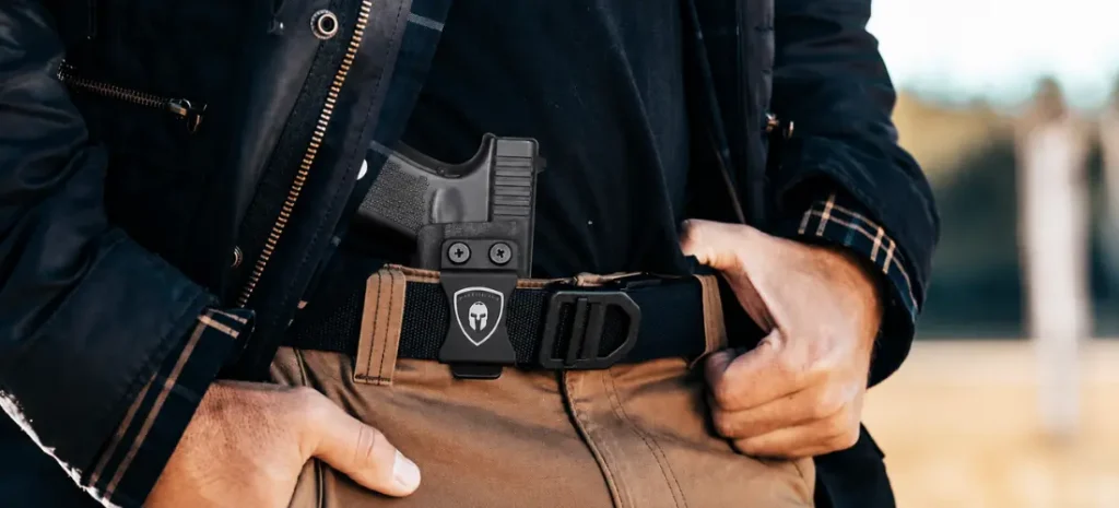 Man carrying a Glock-style pistol in a black appendix holster with a tactical belt and tan pants.