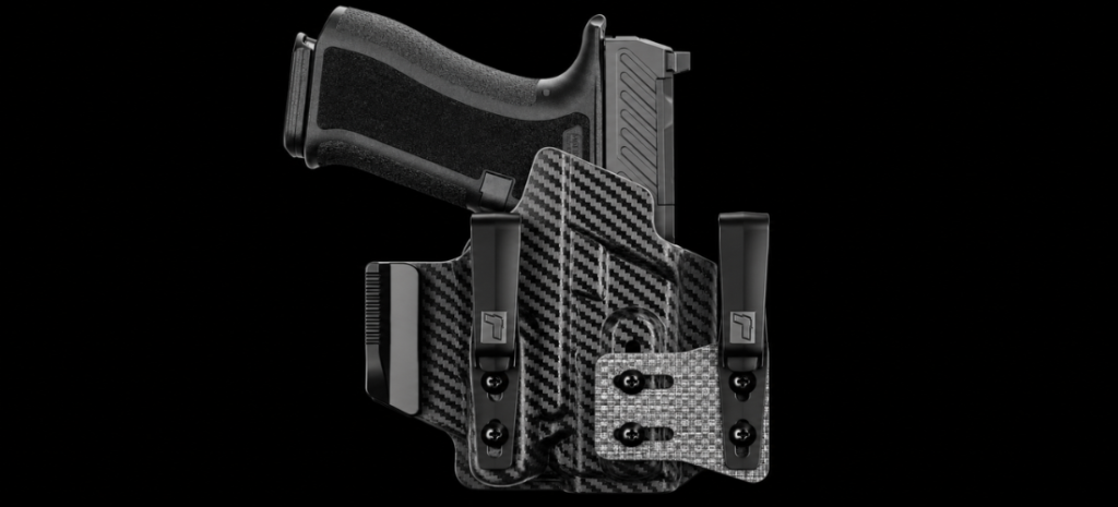 Compact handgun in a carbon-fiber-pattern holster with belt clips on a black background.