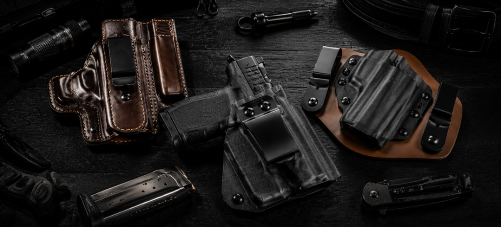 Multiple concealed carry holsters and compact handguns arranged on a dark tabletop with tactical EDC accessories.