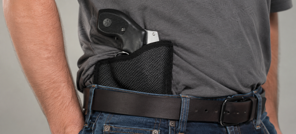 Man wearing a black textured holster with a compact handgun at the waistband.