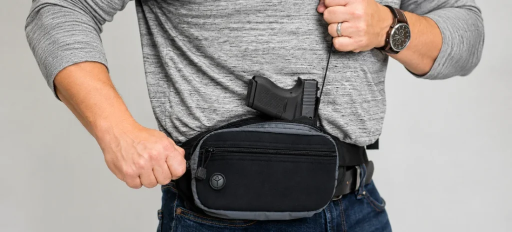 Close-up of a man wearing a black waist pack with a handgun partially visible above it.