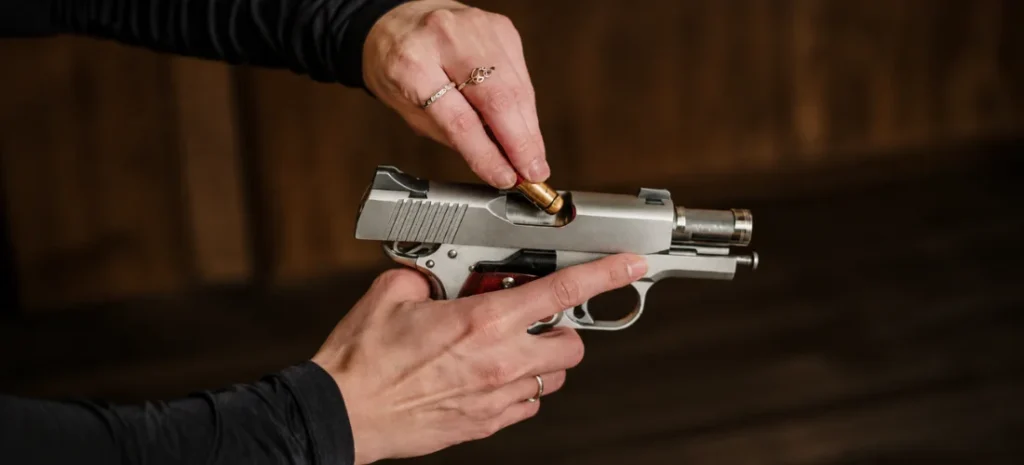 Hands inserting a LaserLyte training cartridge into an unloaded semi-automatic pistol for dry-fire practice.