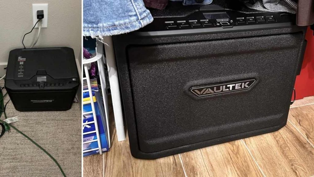 A black VAULTEK MX Series safe beside a closet, partially obscured by clothes, with a power cord visible against a beige wall backdrop.