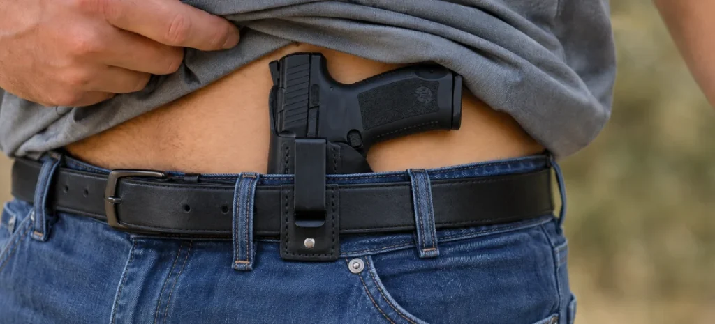 Man wearing a handgun in a black leather IWB holster.