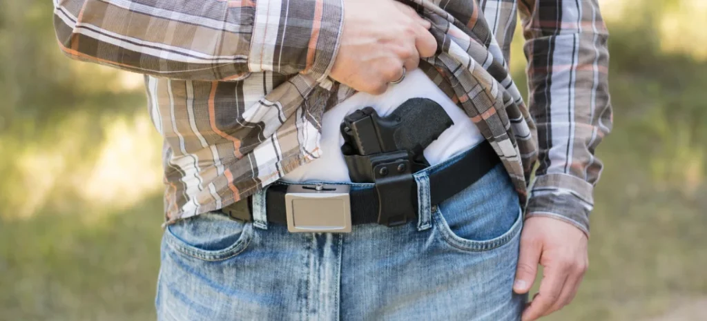 Handgun secured in a black IWB holster under a plaid shirt.